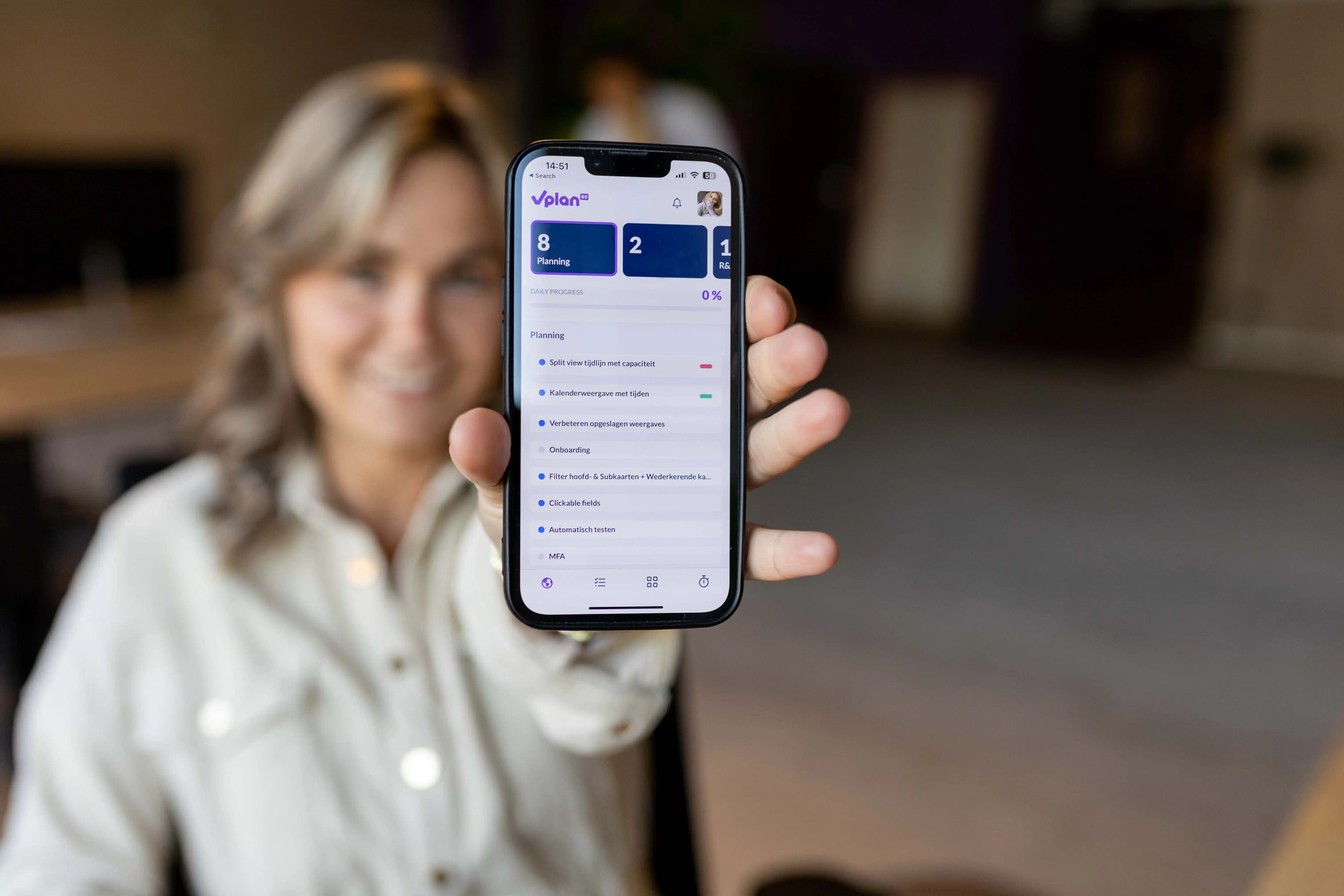 Medewerker die een telefoon vasthoudt met de vPlan app.